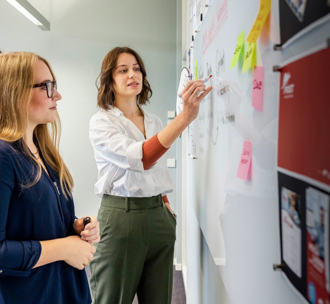 Das Bild zeigt zwei Frauen, wobei eine ein Duales Studium Betriebswirtschaft - Industrie als Bachelor absolviert.