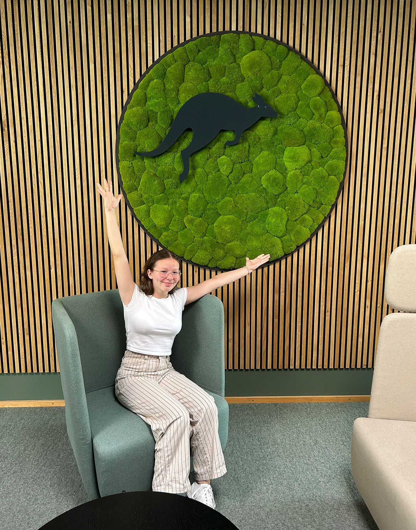 Das Bild zeigt Miri vom dem MediaLogistik-Logo mit Moos sitzend, die für genialsozial einen Tag bei MediaLogistik verbracht hat.